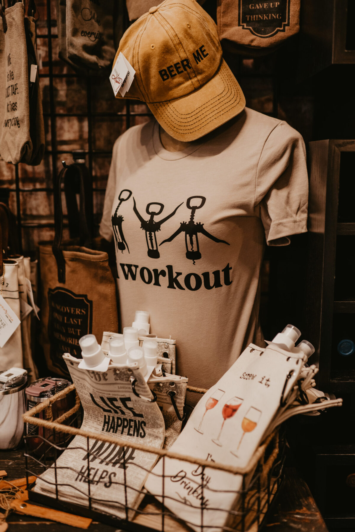 Shop display with a yellow cap, graphic tee, and canvas flasks